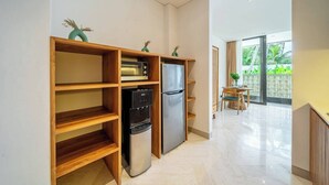 A modern kitchen with built-in appliances, a water dispenser, and a dining area with a table and chairs. - Cozy 1BR in Serene Ubud - Kitchen, Balcony, Pool (Gianyar Regency)