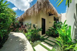 A thatched-roof structure with a door labeled 'Villa Soma,' surrounded by lush tropical plants and a concrete pathway. - Designer 1BR Villa in Serene Ubud - Pool + Garden (Gianyar Regency)