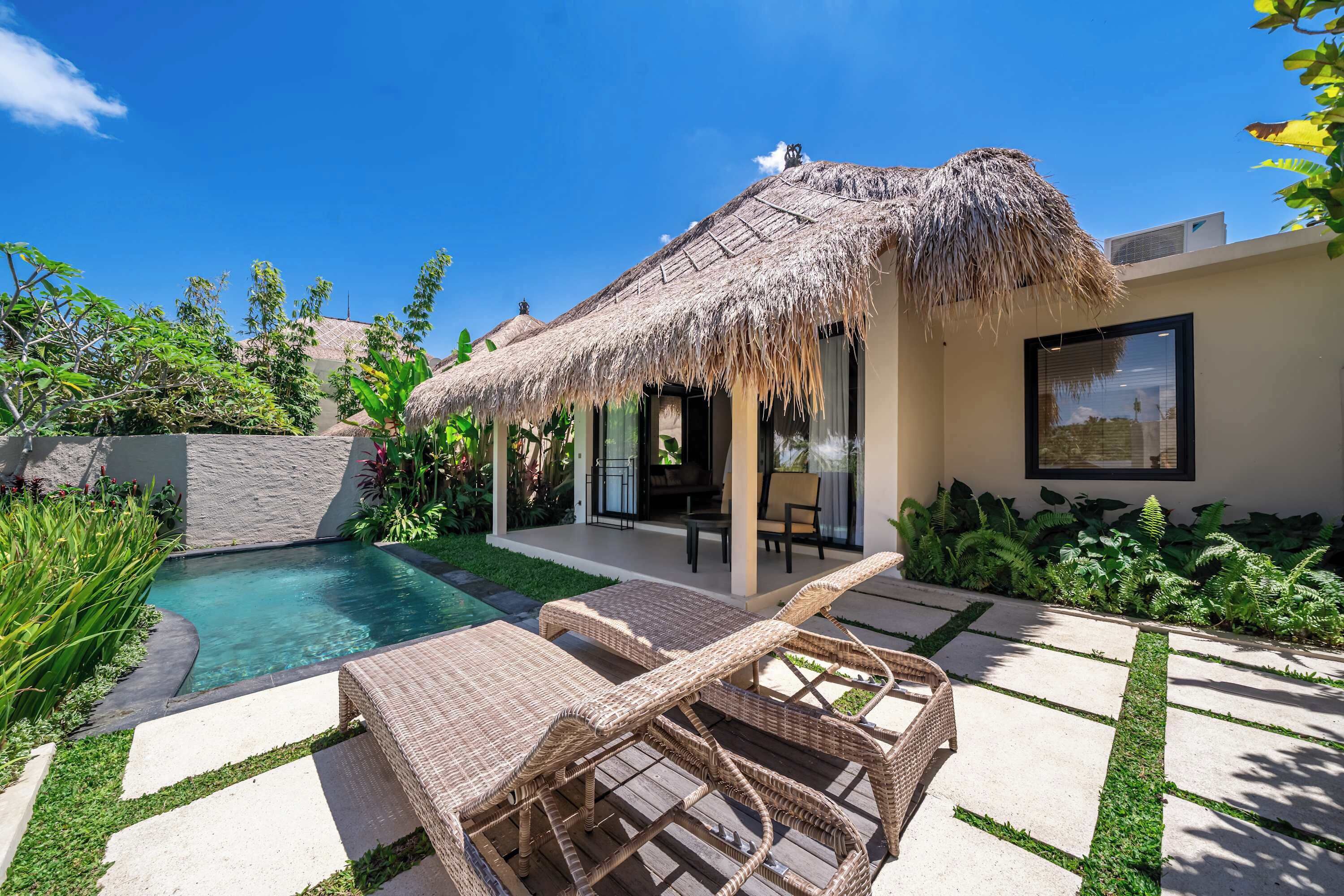 Une maison moderne dotée d’une structure à toit de chaume, d’une piscine et de mobilier d’extérieur.