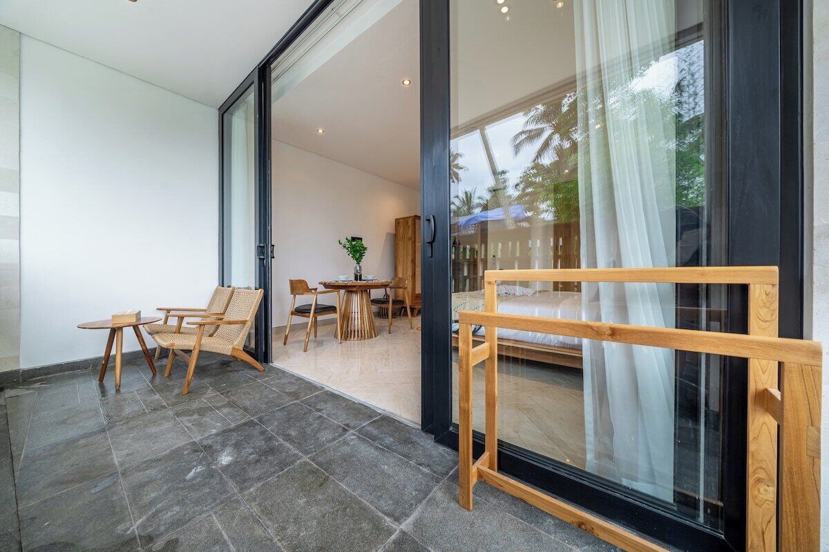 Ein modernes Interieur mit einer Glastür, die auf einen Balkon führt, Holzmöbel und Blick ins Freie.