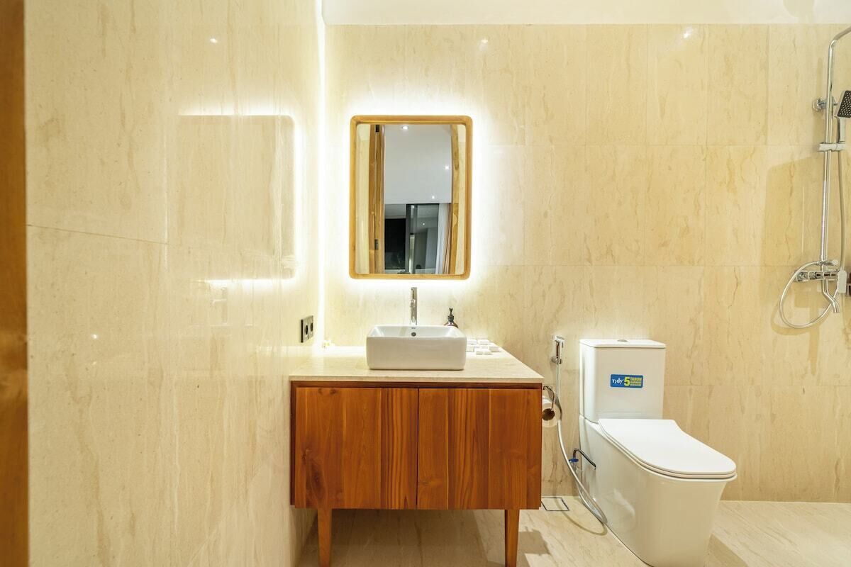 Ein modernes Badezimmer mit einem Holzlagerflächezerspanung, einem weißen Waschbecken, einem Spiegel und einer Toilette.