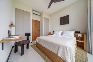 Ein Schlafzimmer mit einem Bett, Nachttischen, einem Schreibtisch, einem Stuhl, einer Stehlampe und einem Deckenventilator.
