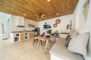 A modern kitchen with a wooden ceiling, a dining table, and a sofa with cushions. - Casa Sud Villa - Modern 3BR w Pool, Outdoor Lounge & Beach Access (Kabupaten Badung)