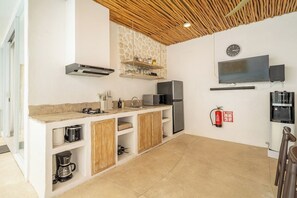 Eine moderne Küche mit Einbauherd, Mikrowelle und Kühlschrank. Eine Holzbalkendecke und ein an der Wand befestigter Feuerlöscher sind vorhanden.