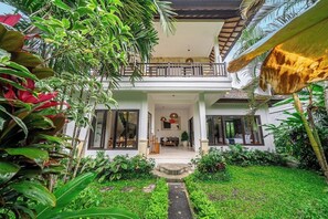 A two-story house with a balcony, surrounded by lush greenery and a well-maintained garden. - New 2BR Villa in Modern Ubud Complex w Spa+2 Pools (Ubud)