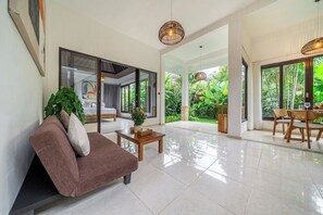 A spacious living area with a sofa, coffee table, and dining table. - New 2BR Villa in Modern Ubud Complex w Spa+2 Pools (Ubud)
