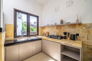 A kitchen with a large window, a gas stove, and a sink. - Chic 2BR Villa in Calm Ubud Complex w Spa+2 Pools (Kabupaten Gianyar)