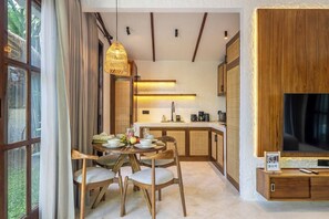 Eine moderne Küche mit Holzausstattung, einem Esstisch mit Stühlen und einem großen Flachbildfernseher an der Wand.
