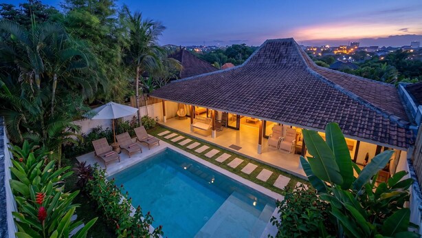 A villa with a swimming pool, outdoor seating, and a view of the city at dusk. - Designer 3BR Villa w Garden Bath & Pool • Ubud (Gianyar Regency)