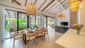 A modern dining area with a large table, chairs, and hanging light fixtures. - Designer 3BR Villa w Garden Bath & Pool • Ubud (Gianyar Regency)