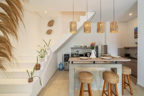 Une cuisine moderne dotée d’un îlot central, de tabourets de bar et de luminaires suspendus.