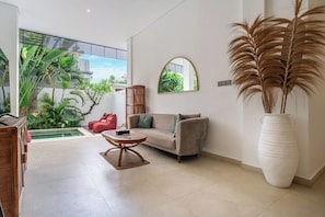 Un salon moderne avec un canapé, une table basse et un grand vase rempli de plumes d’herbe des pampas.
