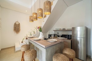 A modern kitchen with a central island, stainless steel appliances, and woven stools. - Arawan Villa - Tropical 3BR Retreat in Canggu w Pool & Patio (Kabupaten Badung)