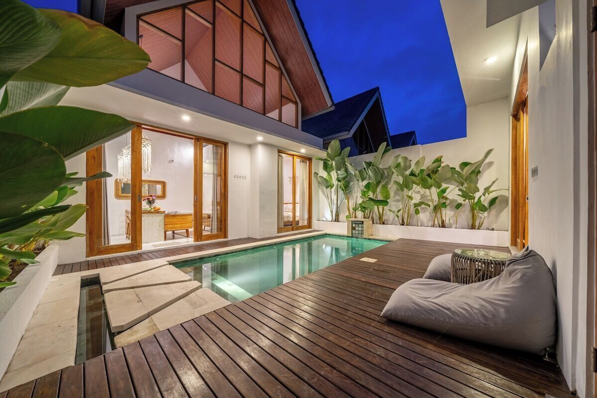 Ein moderner Poolbereich im Freien mit Holzterrasse, einer Sitzecke und Blick auf das Haus.