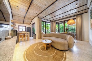 Una sala de estar moderna con un sofá grande, una mesa de centro redonda y un comedor con una mesa y sillas.