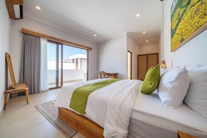 A hotel room with a bed, a chair, a desk, and a view of the outside. - Chic 3BR in Prime Sanur w Pool & Beach Access (Kota Denpasar)