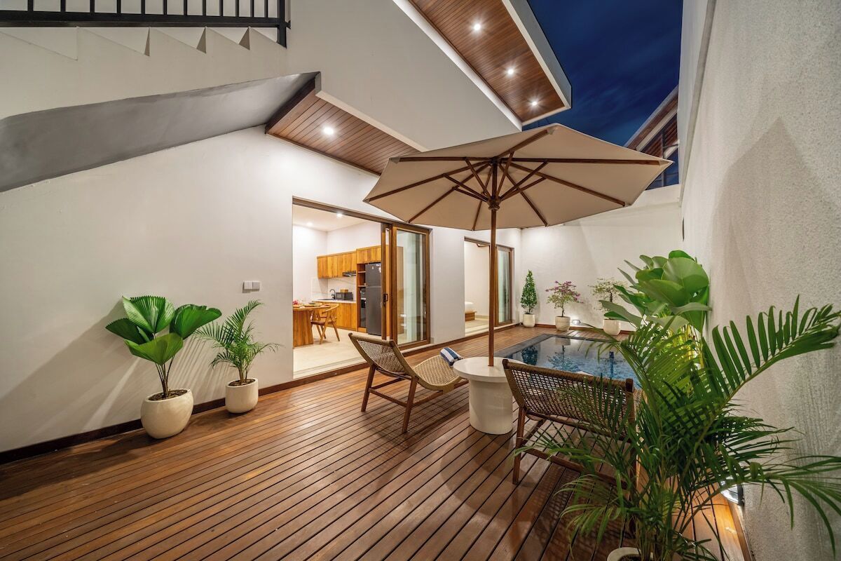 A modern outdoor patio with wooden flooring, a pool table, and lounge chairs.