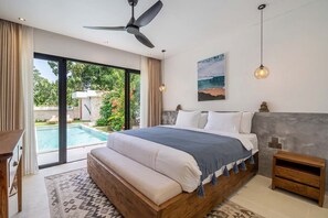 Ein Schlafzimmer mit einem großen Bett, einem Deckenventilator, Blick auf einen Swimmingpool und einem Bild an der Wand.