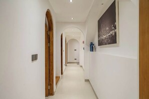 Ein Korridor mit weißen Wänden, Holztüren und einem gerahmten Bild an der Wand.