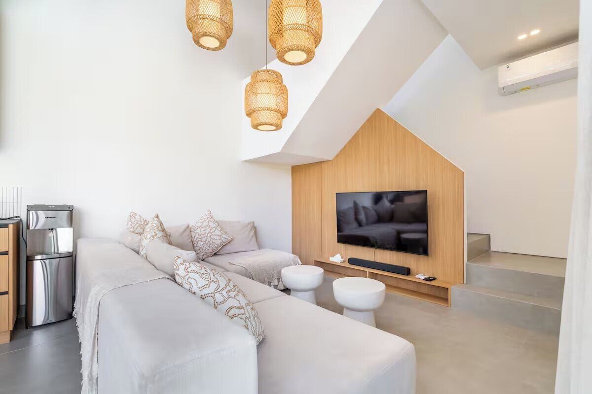 Un salon moderne comprenant un canapé, des poufs, un téléviseur à écran plat et un mur en bois intégré.