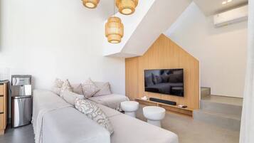 Un salon moderne comprenant un canapé, des poufs, un téléviseur à écran plat et un mur en bois intégré.