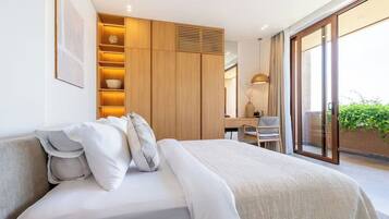 Une chambre moderne avec un grand lit, une armoire intégrée, un bureau et un balcon agrémenté de plantes.