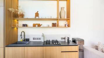 Une cuisine moderne avec des meubles en bois, un plan de travail noir et une étagère intégrée au-dessus de l’évier.