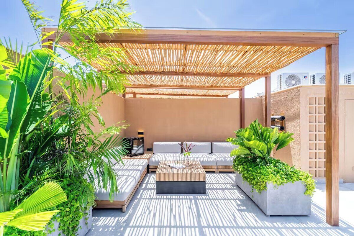 Un espace extérieur aménagé avec une pergola, des sièges confortables, une table basse et des plantes en pot.