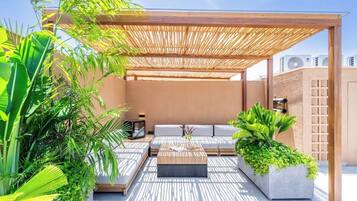 Un espace extérieur aménagé avec une pergola, des sièges confortables, une table basse et des plantes en pot.