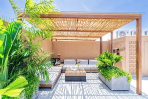 Un espace extérieur aménagé avec une pergola, des sièges confortables, une table basse et des plantes en pot.