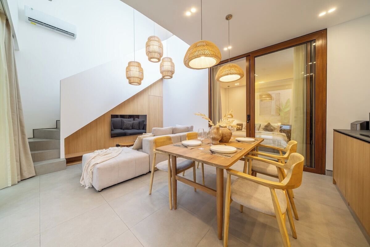 Un salon moderne comprenant un coin repas, un escalier et une cuisine.