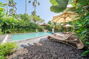 A pool area with lounge chairs and umbrellas, surrounded by tropical vegetation. - Serene 2BR Villa in Ubud Complex w Spa & 2 Pools (Kabupaten Gianyar)