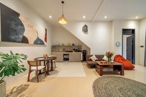 A modern living room with a dining area, kitchen, and a staircase leading to an upper level. - Serene 2BR Villa in Ubud Complex w Spa & 2 Pools (Kabupaten Gianyar)