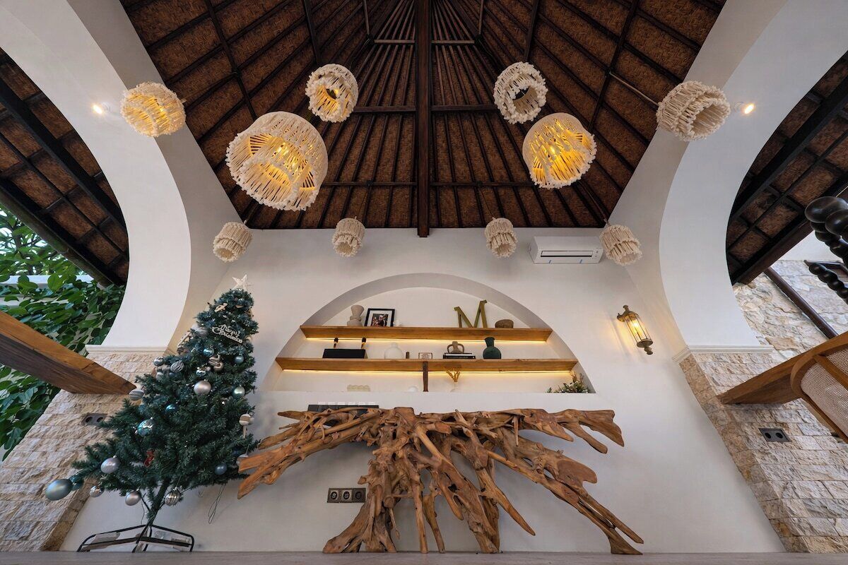 A modern interior with a wooden ceiling, decorative light fixtures, a Christmas tree, and a unique wooden sculpture.