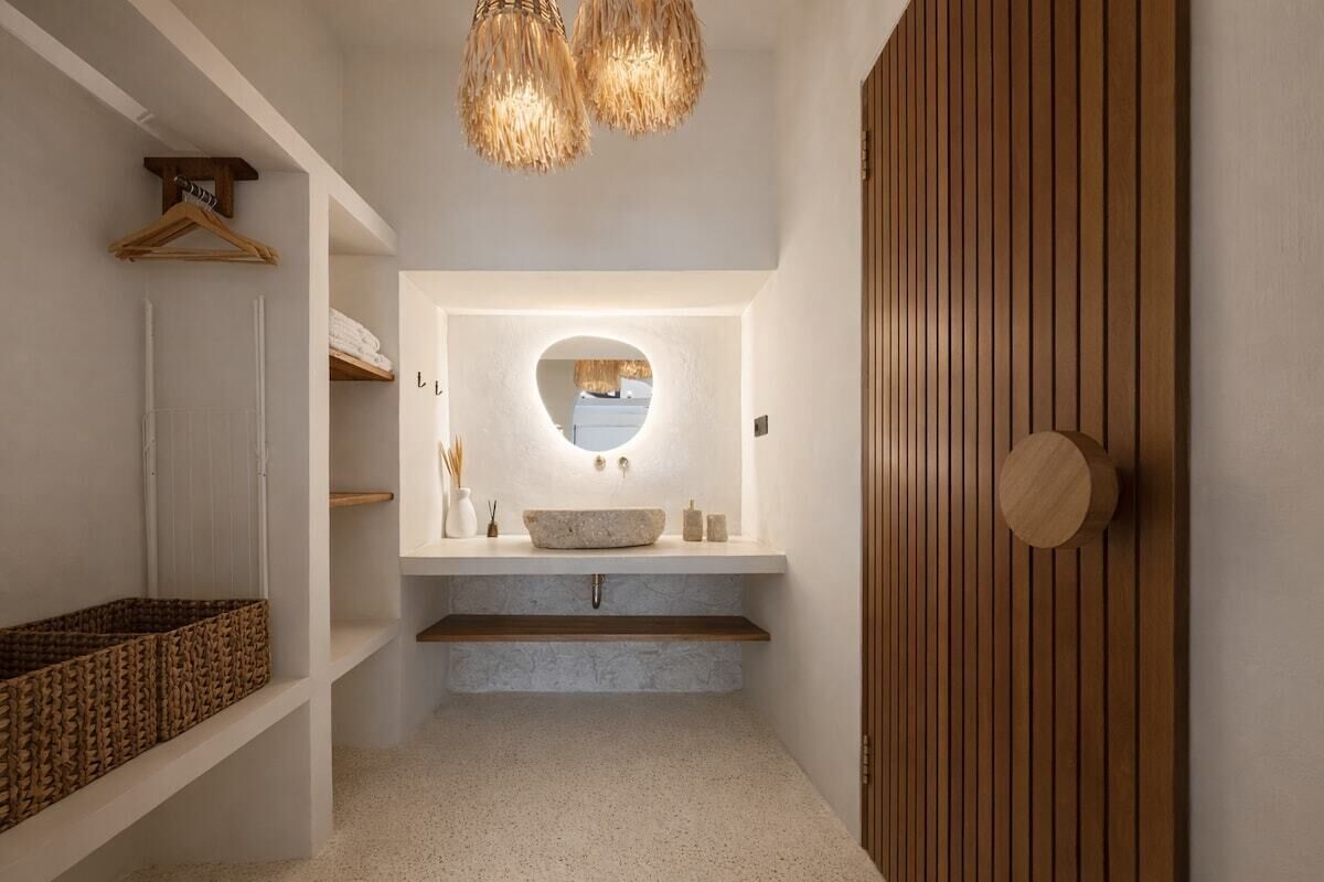 A modern bathroom with a freestanding sink, a round mirror, and a wooden door.