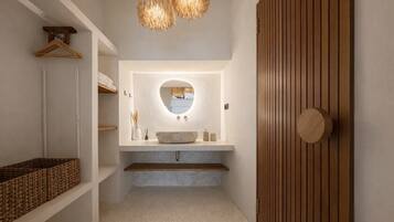 A modern bathroom with a freestanding sink, a round mirror, and a wooden door.