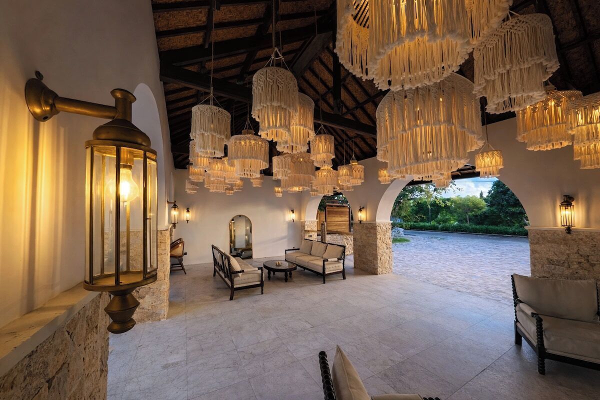 An outdoor seating area with multiple chairs and tables, surrounded by stone walls and a vaulted ceiling.
