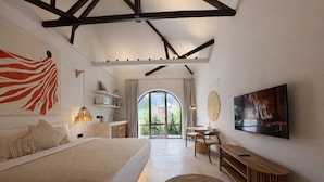 Un dormitorio con cama, escritorio, televisor y un amplio ventanal.