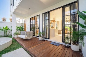 Ein modernes Haus mit einer Holterrasse, großen Glasfenstern und einem Hängesessel.