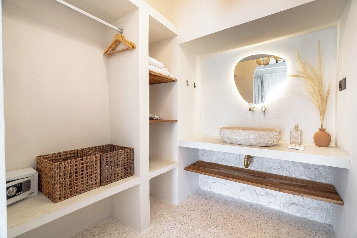 Un baño moderno con una bañera independiente, un espejo redondo y un tocador blanco.