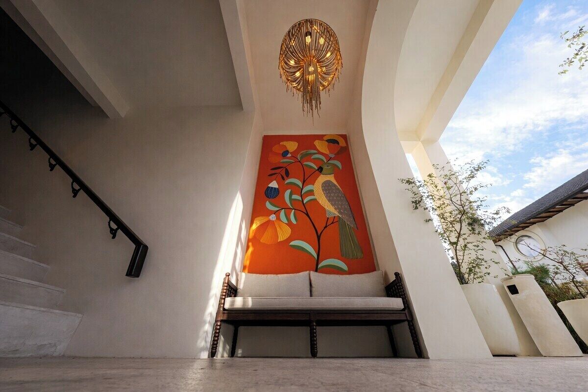 Een trap met een modern ontwerp, een wanddecoratie van een vogel, en een hanglamp.