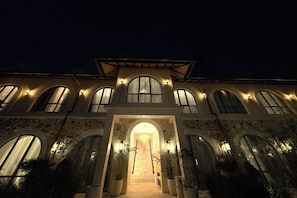 A large building with multiple arched windows and a central entrance with a chandelier. - Chic Apartment Next to Sanur Beach + Pool & Garden (Denpasar Selatan)