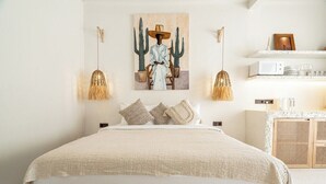 Une chambre avec un grand lit, une œuvre d’art accrochée au mur, une lampe suspendue et une étagère avec divers objets.