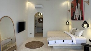Ein Schlafzimmer mit einem Bett, einem Fernseher, einem Spiegel, einem Gemälde und einer Pendelleuchte.