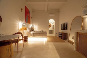 Uma sala de estar com mesa de jantar, cadeiras, sofá, televisão e lareira.