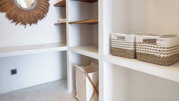 A storage area with white shelving, a hanging mirror, and two woven baskets.