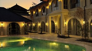 A large building with multiple arched windows and a swimming pool in the foreground. - Brand New Apartments in Sanur+500m to Ocean+Pool (Kota Denpasar)