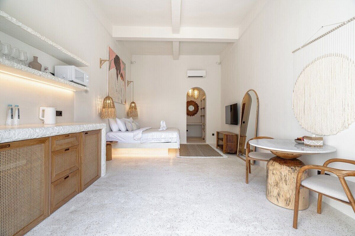 Een moderne slaapkamer met een bed, nachtkastje en spiegel. Er is een zithoekje met een ronde tafel en stoelen.