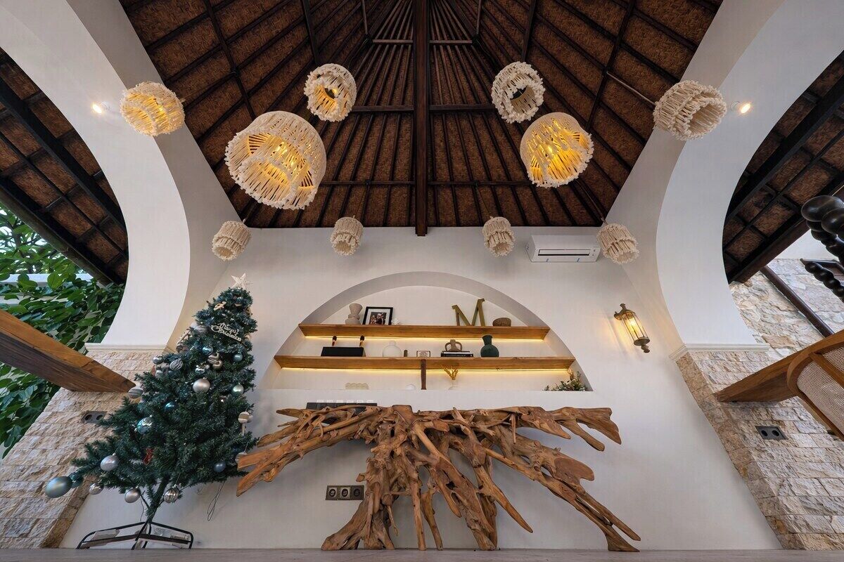 A modern interior with a wooden ceiling, decorative light fixtures, a Christmas tree, and a unique wooden art piece.