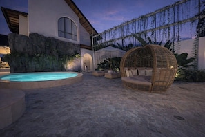 A pool area with a hot tub, stone flooring, and a hanging chair. - New Cozy 1BR Next to the Ocean w Pool+Patio+Garden (Kota Denpasar)
